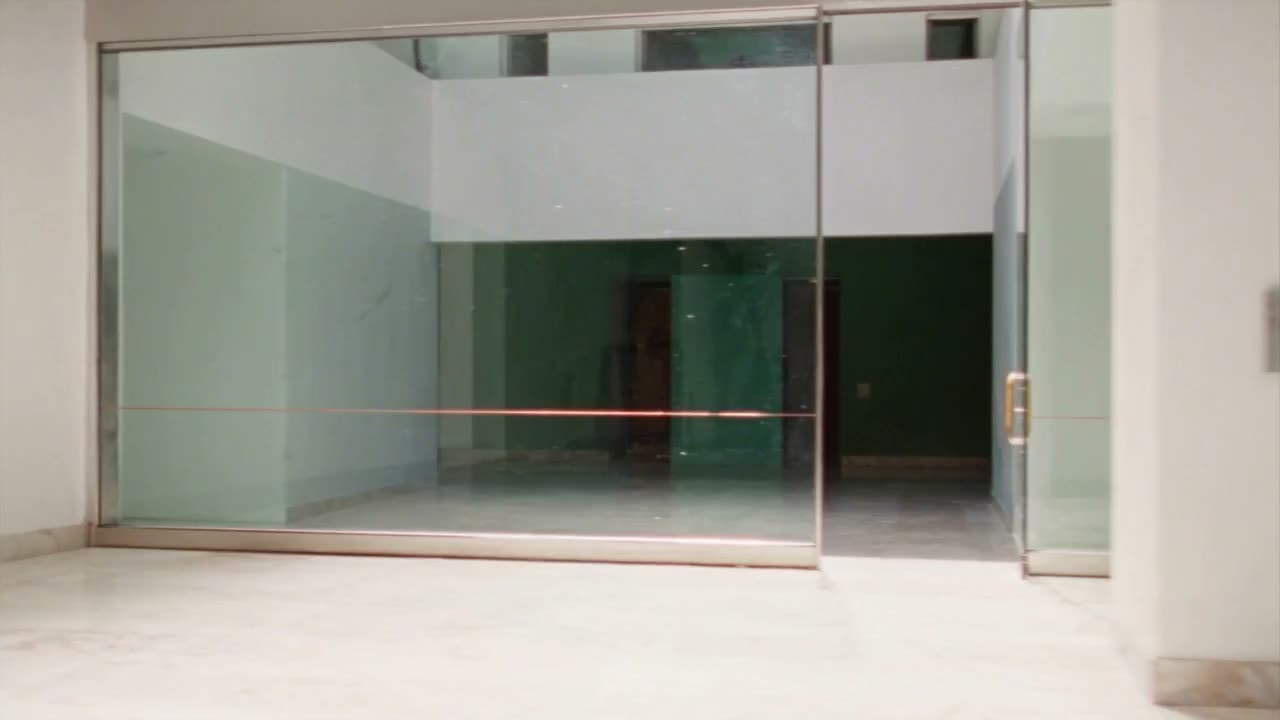 Langsame Vorwärtsfahrt aus abstraktem Licht durch transluzente Glasflächen in einen hellen Eingangsbereich.